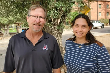 two people, standing in front of a tree, smiling