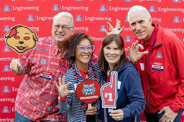 four people smiling, several holding Univ of AZ SWAG