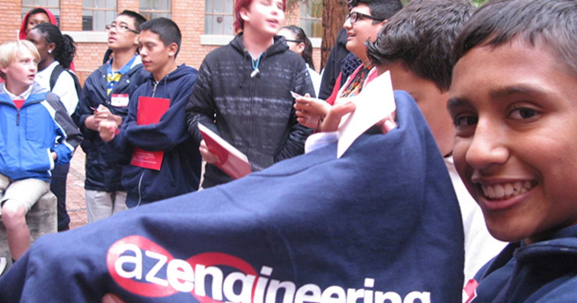 student smiling, holding up a UA t-shirt