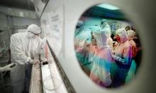 Reflected in a wafer, students gather to watch lab manager Omid Mahdavi run another wafer, which they are building, through part of the process in the clean room. The newest UA semiconductor processing lab is open to graduate and undergraduate students. Photo courtesy Arizona Daily Star