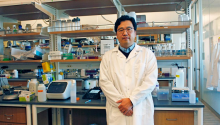 Assistant professor of materials science and engineering Minkyu Kim standing in a laboratory surrounded by beakers and scientific devices. 