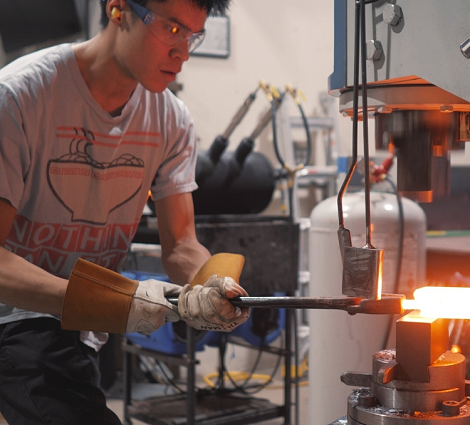 MSE alum Don Nguyen putting red-hot steel into a press